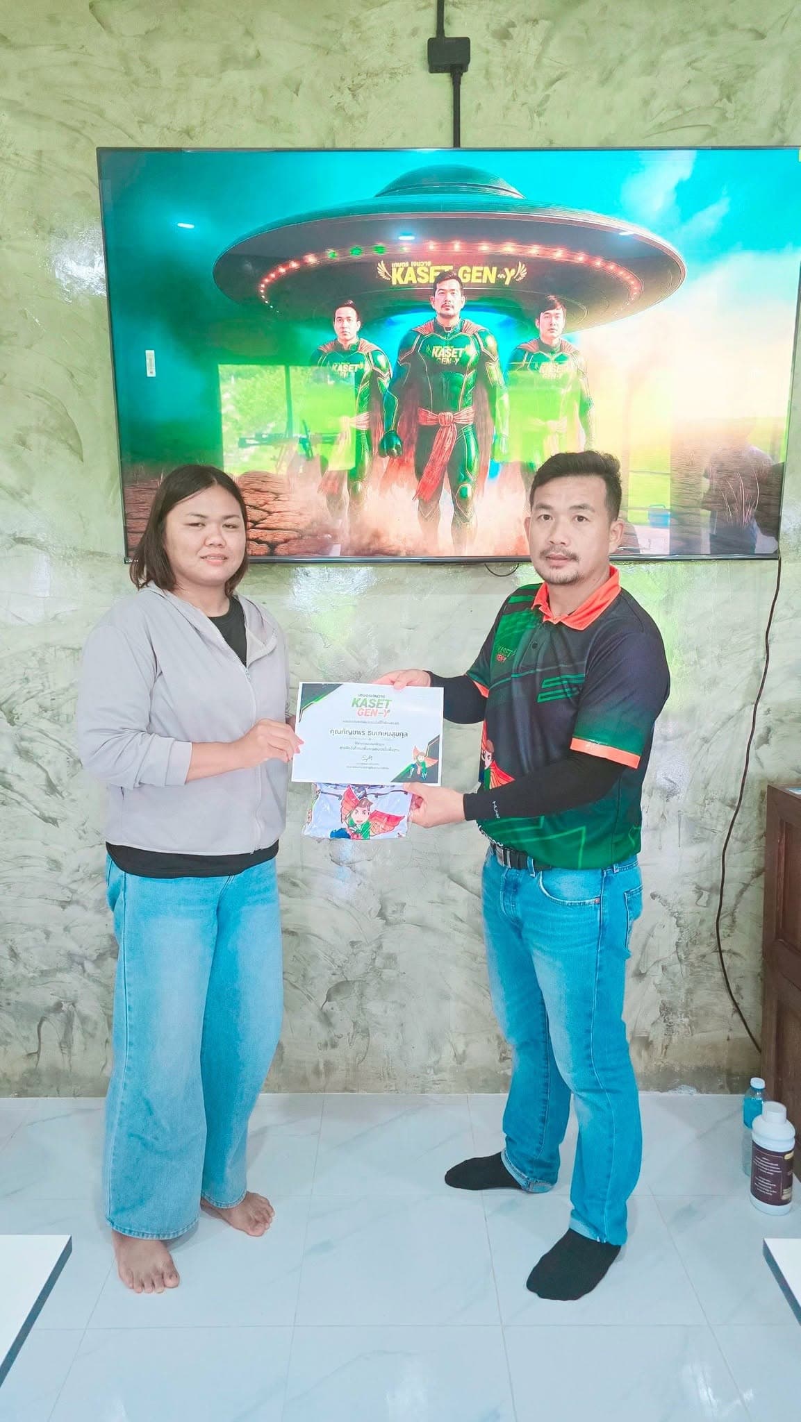 ผู้เข้าอบรมหญิงเสื้อแจ็กเก็ตสีเทารับเกียรติบัตรจากครูฝึก