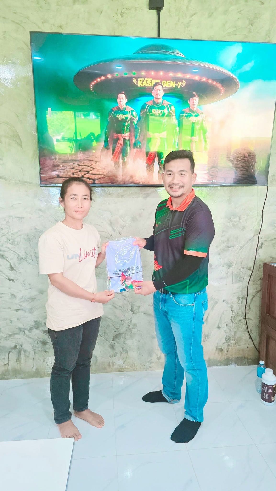 ผู้เข้าอบรมหญิงรับถุงของที่ระลึกจากครูฝึก หน้าจอโทรทัศน์