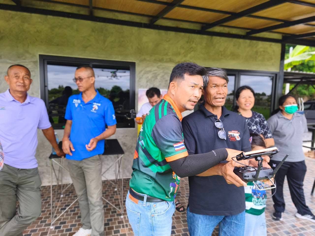 ครูฝึกโอบประคองผู้เข้าอบรมที่ถือรีโมตควบคุม
