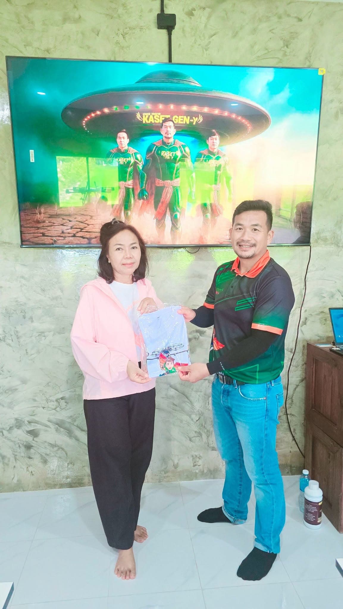 ผู้เข้าอบรมหญิงเสื้อสีชมพูรับถุงของที่ระลึกจากครูฝึก