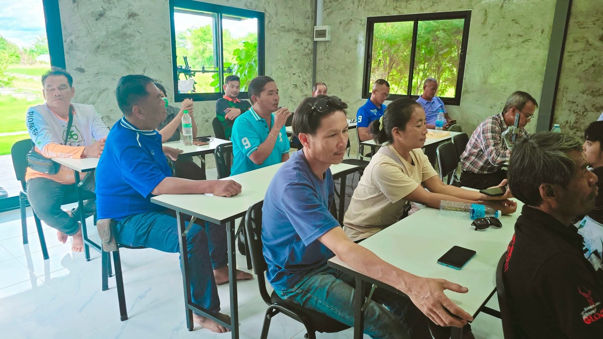 ผู้เข้าอบรมนั่งฟังที่โต๊ะเรียน บางคนกำลังพูดคุยแลกเปลี่ยนกัน