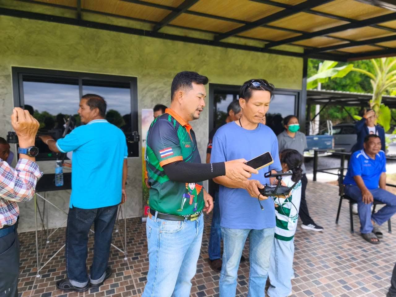 ครูฝึกถือรีโมตอธิบายให้ผู้เข้าอบรมเสื้อสีฟ้าดู